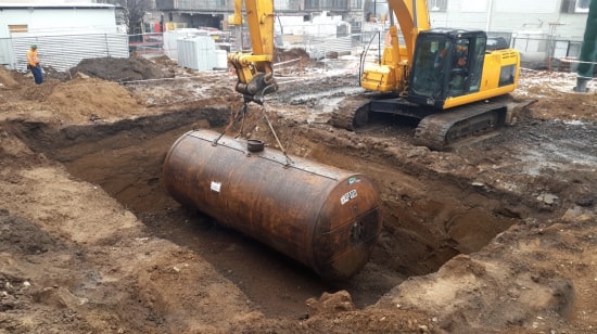 Koparka umieszcza w wykopie stalowy zbiornik na wodę